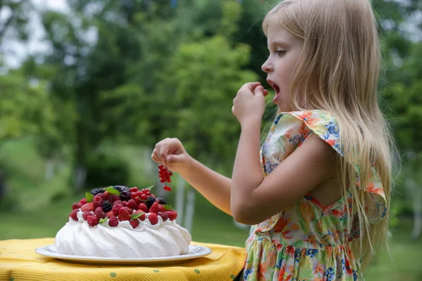 Çiçekli yaz elbisesi içinde Pavlova pastası yiyen sevimli küçük kız.