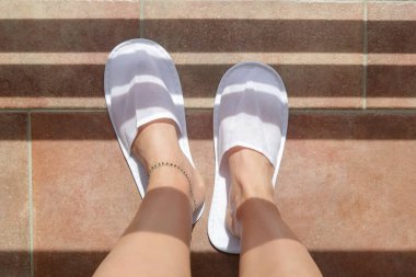 Balkonda beyaz otel terliklerinin içinde ayaklar