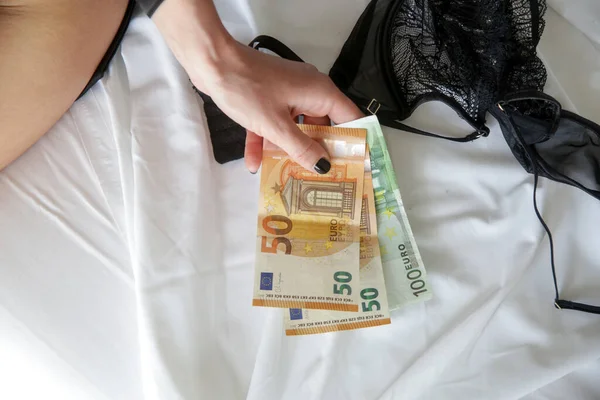 Money and young woman in hotel room as a symbol of prostitution, modern slavery and human trafficking. Human trafficking and the hotel industry concept.