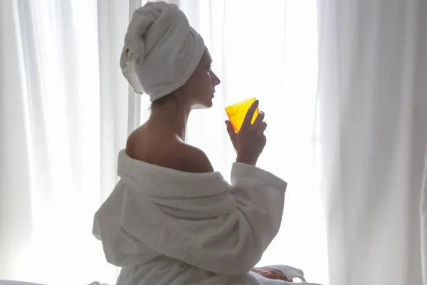 タオルに包まれた若い美しい女性は 窓の横に液体コラーゲンやビタミンサプリメントを飲んで 健康的な朝のライフスタイルの概念 — ストック写真