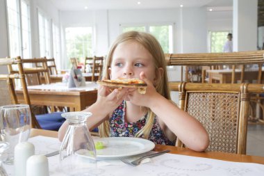 Restoranda pizza yiyen küçük kız. 