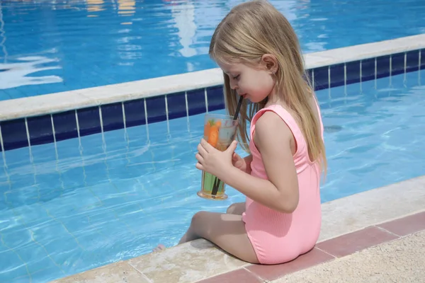 暑い夏の日の間にプールサイド 水分補給と健康的な食事療法でリフレッシュドリンクを持っている愛らしい女の子 — ストック写真