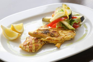 Restoran masasında ızgara sebzeli ızgara tavuk.