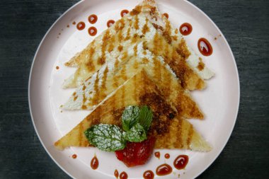 Çikolata şurubuna batırılmış krepler taze çilek ve nane yaprağıyla.