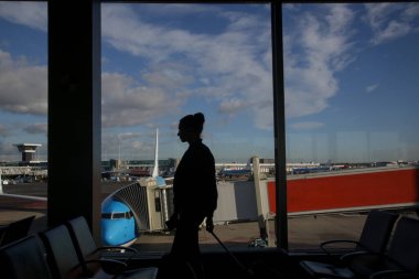 Havaalanı terminalinde bavullu bir kadın yolcunun silüeti.