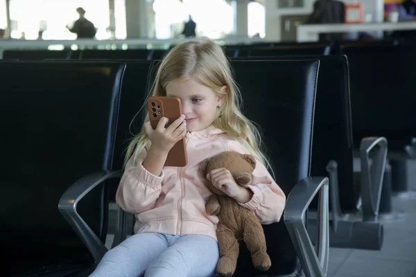 Klein Meisje Zit Een Luchthaven Vertrekhal Met Teddybeer Tevreden Spelen — Stockfoto