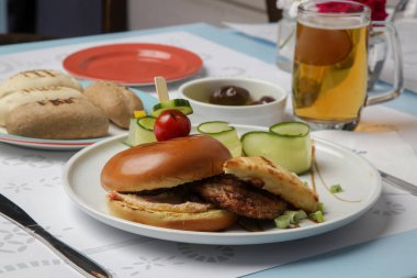 Güzel gündelik yemek: Restoran masasında servis edilen salatalık dilimli klasik burger