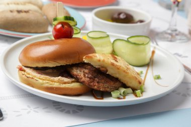 Güzel gündelik yemek: Restoran masasında servis edilen salatalık dilimli klasik burger