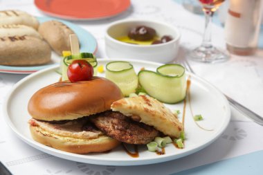 Güzel gündelik yemek: Restoran masasında servis edilen salatalık dilimli klasik burger