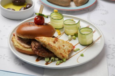 Güzel gündelik yemek: Restoran masasında servis edilen salatalık dilimli klasik burger
