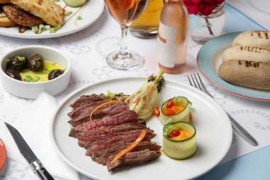 Lokanta masasında biftek sosu servis edilmiş orta pişmiş sığır filetosu.