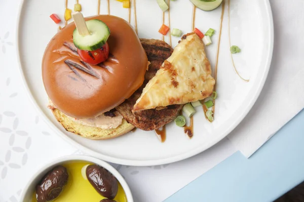 Güzel gündelik yemek: Restoran masasında servis edilen salatalık dilimli klasik burger