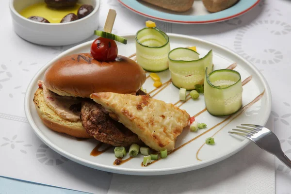 Güzel gündelik yemek: Restoran masasında servis edilen salatalık dilimli klasik burger