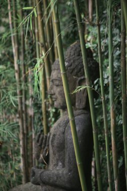Bambu bahçesinde geleneksel Bali taş heykeli