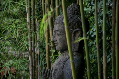 Bambu bahçesinde geleneksel Bali taş heykeli