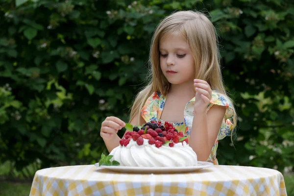 Çiçekli yaz elbisesi içinde Pavlova pastası yiyen sevimli küçük kız.