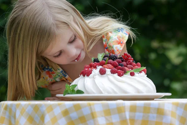 Çiçekli yaz elbisesi içinde Pavlova pastası yiyen sevimli küçük kız.