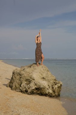 Sahilde leopar desenli keten elbiseli kadın modelin açık hava portresi, şık ve zarif yaz modası.