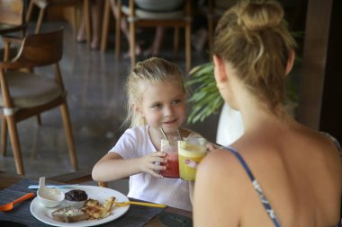 Young woman having pleasant time with her daughter in the restaurant. Concept of family dining in a casual restaurant.