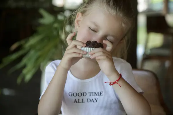 可愛いです5歳の女の子食べるチョコレートマフィンでザレストラン — ストック写真