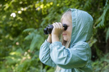 Dürbünle doğayı keşfeden sevimli küçük bir kız. Çocuk dışarıda oynuyor. Çocuklar seyahat, macera ve kuş izleme konsepti.