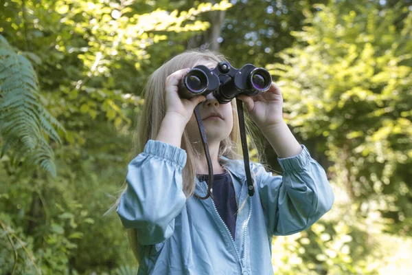 双眼鏡を通して自然を探検するかわいい少女 屋外で遊んでいる子供 子供旅行 アドベンチャー バードウォッチングコンセプト — ストック写真