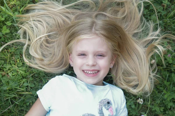 メドウに横たわるロングブロンドの髪を持つ愛らしい少女 トップビュー — ストック写真