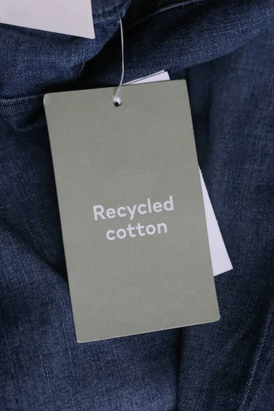 Close up of clothing hang tag. Recycled cotton product details.