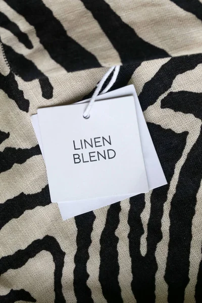 Close up of clothing hang tag. Linen blend product details.