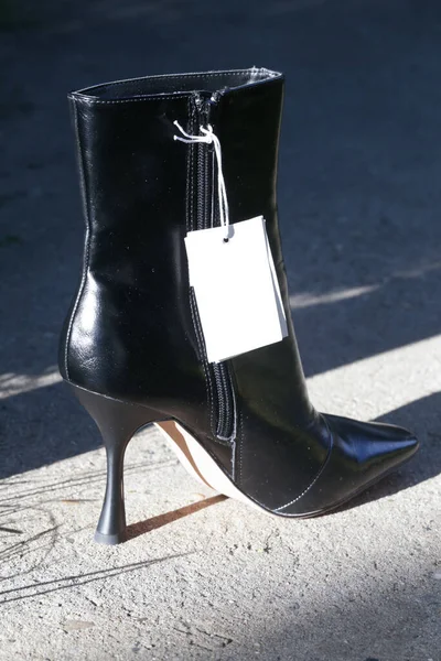 Black leather ankle boots with pointed toe and high heels with blank price tag, product photography