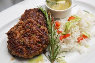 Restoran masasında beyaz pirinç ve biberiyeyle servis edilen kızarmış köfteler.