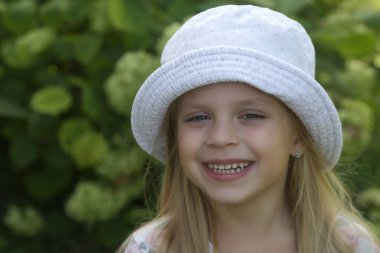 Kovalı şapkalı mutlu küçük kızın açık hava portresi.