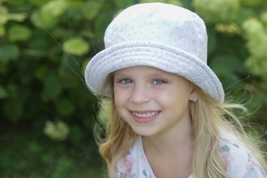 Kovalı şapkalı mutlu küçük kızın açık hava portresi.