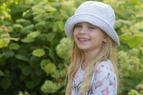 Candid outdoor portrait of happy little girl with bucket hat