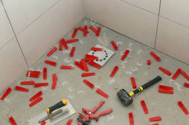 Plastik döşeme sistemi, yerdeki fayanslar için çentikli mala ve lastik çekiç. Banyoya fayans döşeme işlemi. DIY Ev Geliştirme.