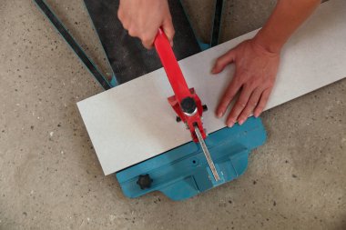 Standart bir fayans kesicisiyle fayanslar kesiliyor. Banyoya fayans döşeme işlemi adım adım yapılıyor. DIY Ev Geliştirme. 