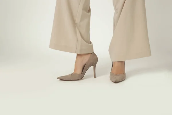 Female model wearing beige smart casual high rise wide leg trousers with high heels. Studio shot.