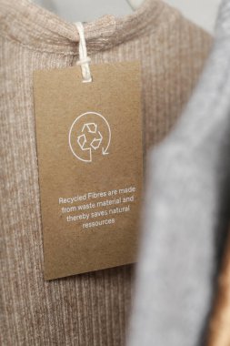 Giysi etiketini geri dönüşüm simgesiyle kapat. Ürün geri dönüşümü kavramı. Sıfır atık, suistainale üretimi, çevre bakımı ve yeniden kullanım kavramı.