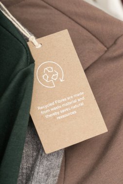 Giysi etiketini geri dönüşüm simgesiyle kapat. Ürün geri dönüşümü kavramı. Sıfır atık, suistainale üretimi, çevre bakımı ve yeniden kullanım kavramı.