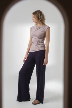 Stüdyo fotoğrafları, rahat basit kıyafetler, kolsuz gömlek ve geniş paçalı pantolon giyen, organik pamuktan yapılmış rahat bir takım elbise.