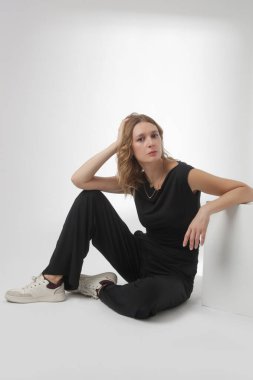 Stüdyo fotoğrafları, rahat siyah kıyafetler, kolsuz gömlek ve geniş paçalı pantolon giyen, organik pamuktan yapılmış rahat bir takım elbise.