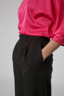 Stüdyo fotoğrafları, sade güzel kıyafetler, ipek pembe bluz ve siyah geniş paça pantolon giyen genç kadın modeller.