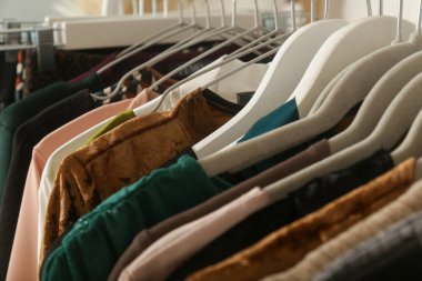 Kadın modası. Askılarda farklı kıyafetler, yakın çekim. İkinci el dükkanında ya da ikinci el mağazasında farklı kullanılmış kadın kıyafetlerinden bir sürü var. Moda endüstrisinde atık sorunu kavramı