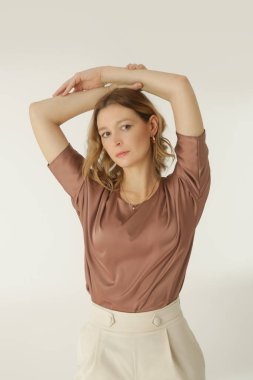 Stüdyo fotoğrafları, sade güzel kıyafetler, ipek saten bluz ve beyaz geniş paça pantolon giyen genç kadın modeller. 