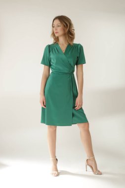 Stüdyo fotoğraflarının serisi. Yeşil ipek saten elbise giyen genç bir kadın model..