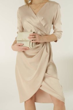 Stüdyo fotoğrafları, bej ipek saten elbise giymiş genç bir kadın modeli..