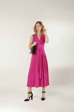 Stüdyo fotoğrafları. Pembe, yapışkan elbise giymiş genç bir kadın model..
