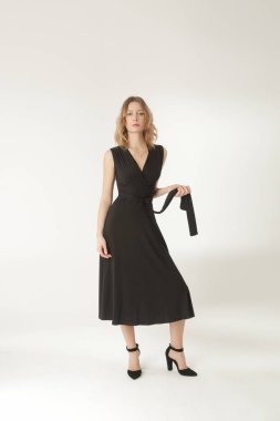 Serie of studio photos of young female model in black viscose wrap dress. 