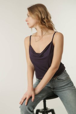 Mor pamuklu bluz ve kot pantolon giyen bir kadın model. Klasik ve basit yaz modası. Stüdyo çekimi. 