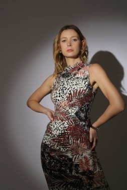 Sahne ışıkları altında, hayvan desenli vücut giysisi giymiş genç bir kadın modelin seri fotoğrafları. Klasik ve basit yaz modası..